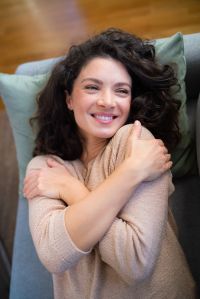 Happy woman feels beautiful while lying on the couch at home