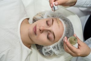 Dermatologist is putting essential oil moisturizing serum on the face of young caucasian women