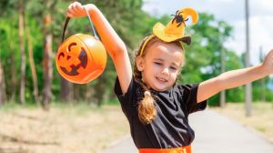 Child in a Halloween costume. trick or treat on the street. Little girl with pumpkin lantern and candy bucket. A child in a witch's hat. Autumn holidays are fun.