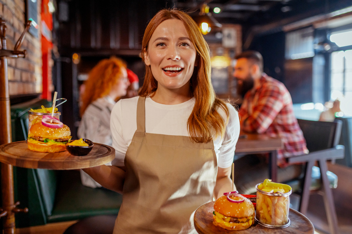 Joyful Service: Cheerful Waitress Serving Gourmet Burgers with a Smile
