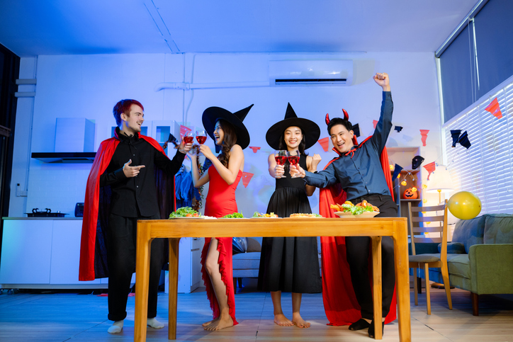 Joyful office Halloween party with coworkers in costumes, celebrating with drinks and laughter, fostering teamwork and festive spirit