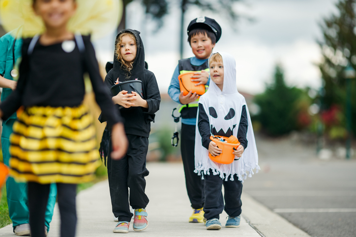 Children Trick Or Treat For Halloween In Residential Neighborhood
